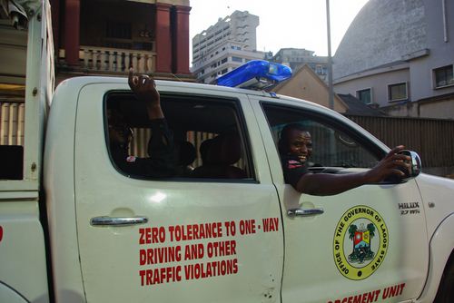 Mopol en liesse, Princess street, Lagos Island Une voiture de la « mobile police » nous dépasse en nous lancant des blagues qu’eux seuls comprennent